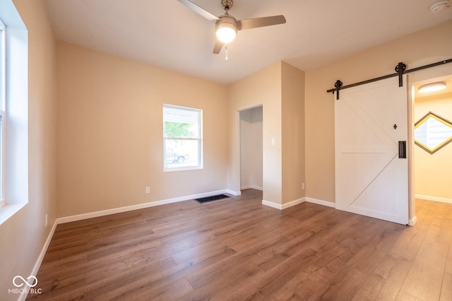 214 S Mcilroy Ave, West Terre Haute, IN 47885 - unfurnished bedroom with wood finished floors, a barn door, multiple windows, and baseboards