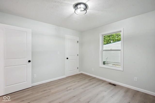 302 Highlawn Ave, Seymour, IN 47274 - unfurnished bedroom with light wood-type flooring, a textured ceiling, and baseboards