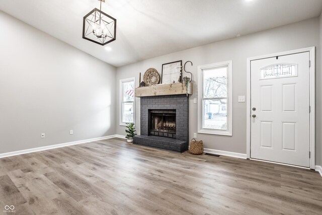 912 Delray Dr, Indianapolis, IN 46241 - unfurnished living room with a chandelier, wood finished floors, a brick fireplace, baseboards, and recessed lighting