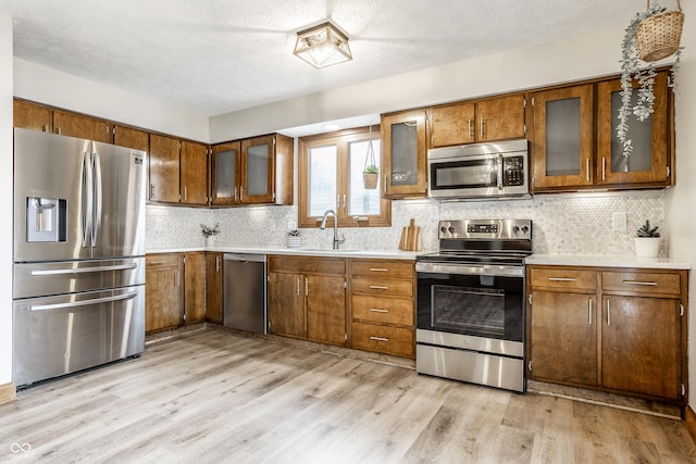 912 Delray Dr, Indianapolis, IN 46241 - kitchen featuring appliances with stainless steel finishes, a sink, brown cabinetry, light countertops, and a textured ceiling