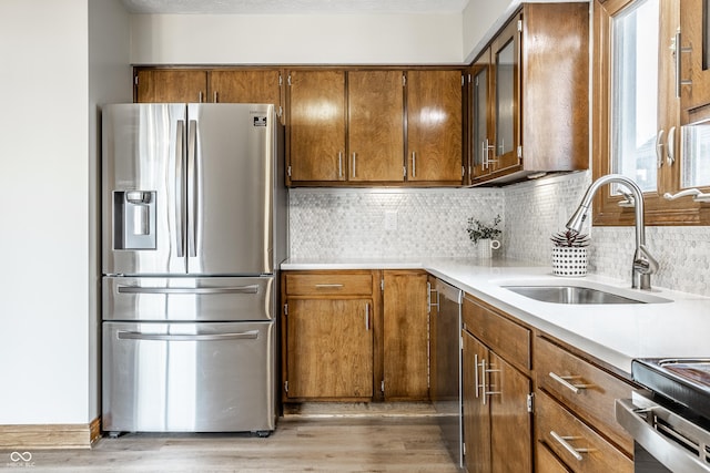 912 Delray Dr, Indianapolis, IN 46241 - kitchen featuring stainless steel appliances, a sink, light wood-type flooring, light countertops, and decorative backsplash