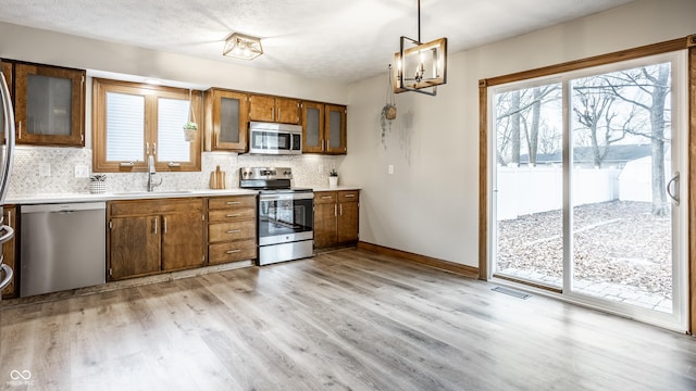 912 Delray Dr, Indianapolis, IN 46241 - kitchen featuring stainless steel appliances, a sink, brown cabinetry, light countertops, and decorative backsplash