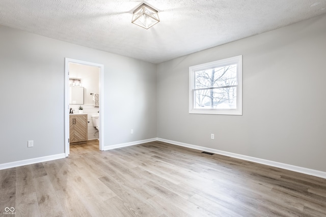 912 Delray Dr, Indianapolis, IN 46241 - unfurnished bedroom featuring light wood-type flooring, a textured ceiling, baseboards, and connected bathroom
