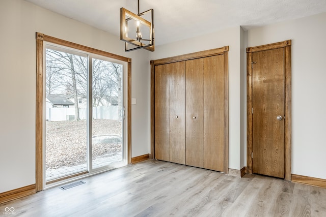 912 Delray Dr, Indianapolis, IN 46241 - unfurnished bedroom featuring access to exterior, light wood-style flooring, a chandelier, baseboards, and a closet