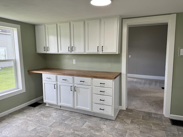 707 N Water St, Hillsboro, IN 47949 - kitchen featuring butcher block countertops, baseboards, white cabinets, and stone finish flooring