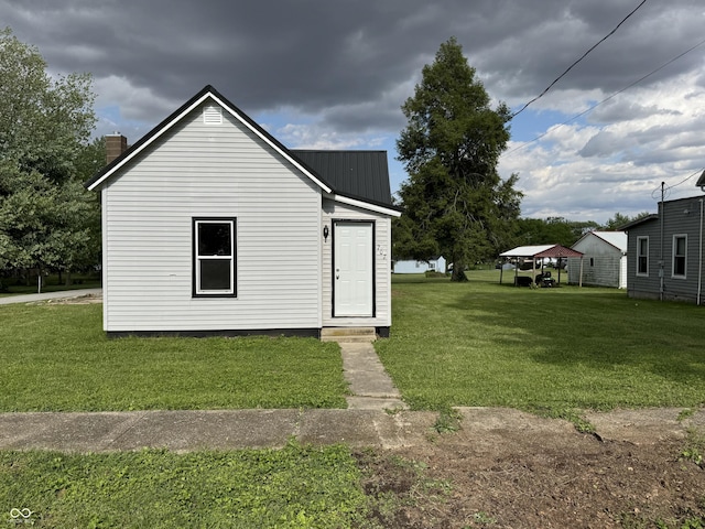 707 N Water St, Hillsboro, IN 47949 - view of property exterior featuring a yard, a chimney, and metal roof