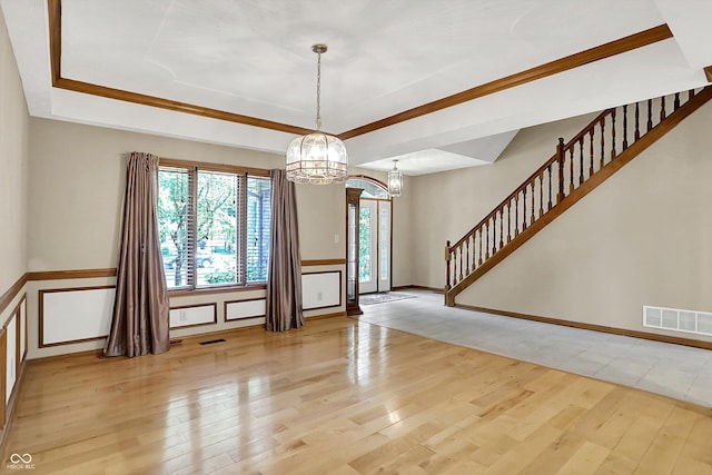 1344 S Fox Paw Dr, New Palestine, IN 46163 - spare room with a chandelier, a tray ceiling, light wood-type flooring, and stairway