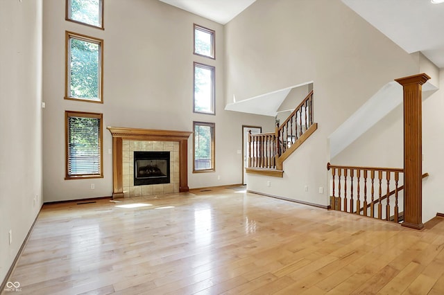 1344 S Fox Paw Dr, New Palestine, IN 46163 - unfurnished living room with a high ceiling, hardwood / wood-style floors, a tiled fireplace, and stairs