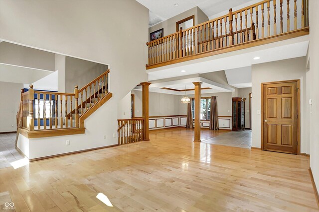 1344 S Fox Paw Dr, New Palestine, IN 46163 - unfurnished living room with decorative columns, a towering ceiling, wood finished floors, and stairs