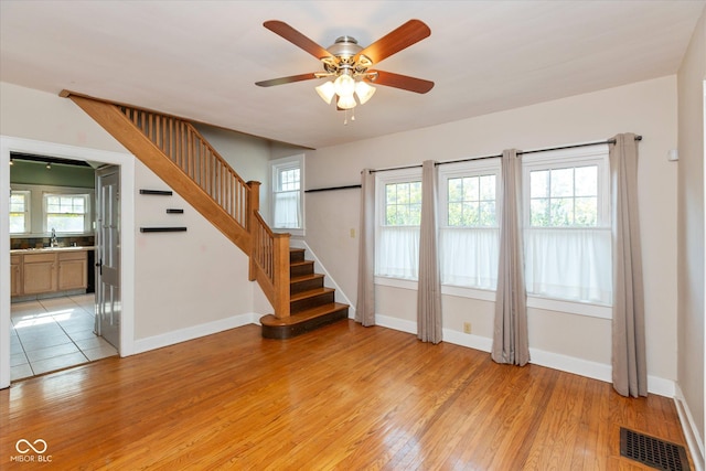 1015 Fairfield Ave, Indianapolis, IN 46205 - unfurnished living room with light wood-style floors, stairs, a sink, ceiling fan, and baseboards