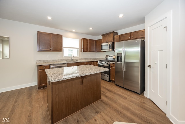 1863 River Birch Dr, Greenfield, IN 46140 - kitchen with appliances with stainless steel finishes, a sink, a kitchen island, dark wood-type flooring, and light stone counters