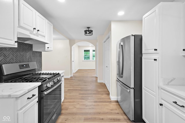 5422 Orange St, Indianapolis, IN 46203 - kitchen with appliances with stainless steel finishes, under cabinet range hood, arched walkways, tasteful backsplash, and white cabinetry