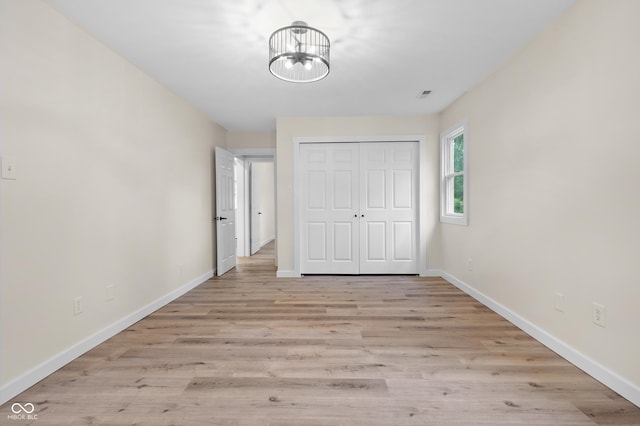5422 Orange St, Indianapolis, IN 46203 - unfurnished bedroom with baseboards, a chandelier, a closet, and light wood-style floors