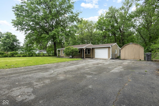 5422 Orange St, Indianapolis, IN 46203 - ranch-style house featuring asphalt driveway, an attached garage, an outbuilding, and view of wooded area