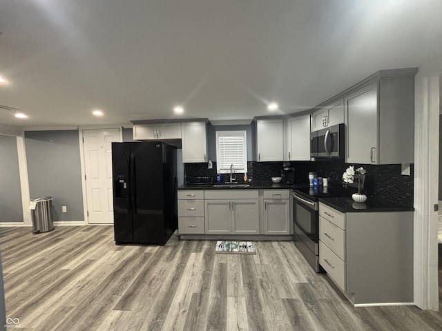 3041 S Rybolt Ave, Indianapolis, IN 46241 - kitchen featuring appliances with stainless steel finishes, dark countertops, light wood-type flooring, decorative backsplash, and a sink