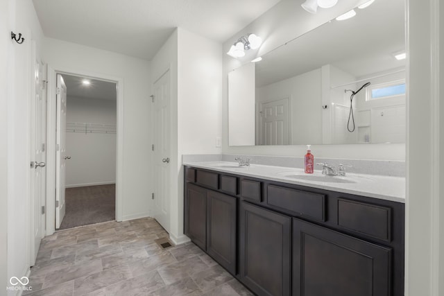 2502 Creekland Dr, Columbus, IN 47201 - bathroom with double vanity, a shower, a walk in closet, baseboards, and stone finish floors