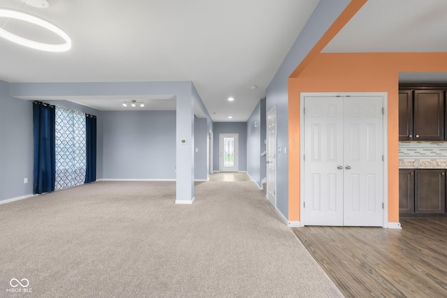 2502 Creekland Dr, Columbus, IN 47201 - unfurnished living room featuring baseboards, light colored carpet, and light wood-type flooring