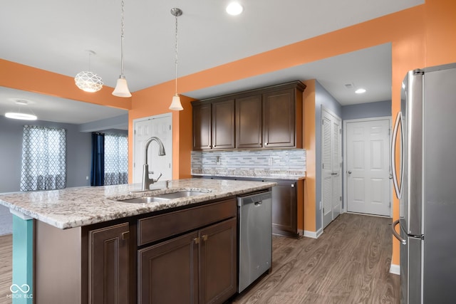 2502 Creekland Dr, Columbus, IN 47201 - kitchen with stainless steel appliances, a sink, wood finished floors, backsplash, and hanging light fixtures