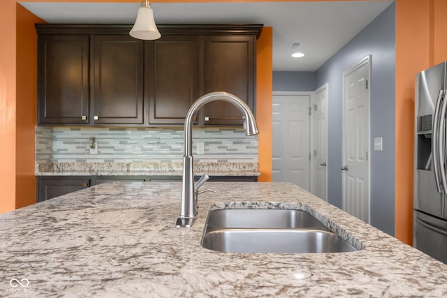 2502 Creekland Dr, Columbus, IN 47201 - kitchen featuring stainless steel fridge, a sink, backsplash, dark brown cabinetry, and light stone counters
