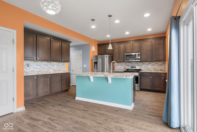 2502 Creekland Dr, Columbus, IN 47201 - kitchen with appliances with stainless steel finishes, backsplash, wood finished floors, dark brown cabinetry, and decorative light fixtures