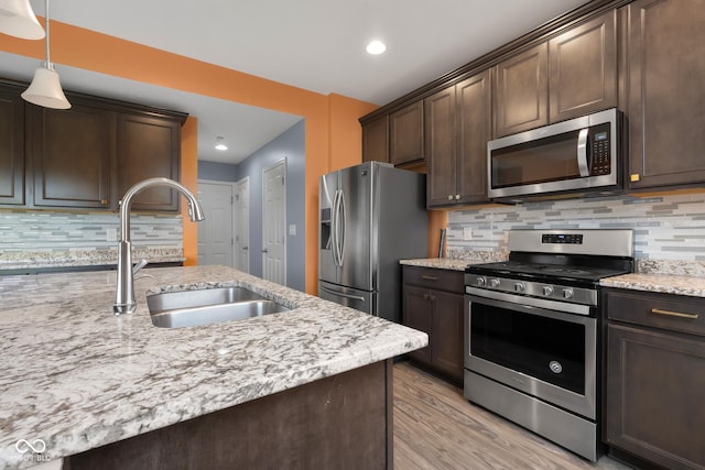 2502 Creekland Dr, Columbus, IN 47201 - kitchen featuring stainless steel appliances, a sink, dark brown cabinetry, light wood-style floors, and decorative backsplash