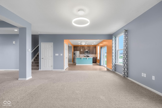 2502 Creekland Dr, Columbus, IN 47201 - unfurnished living room featuring light carpet, stairs, baseboards, and recessed lighting