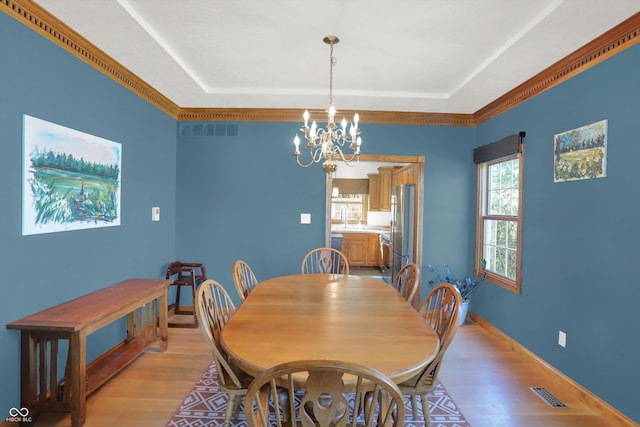 545 Walnut Woods Dr, Greenwood, IN 46142 - dining area with light wood-style flooring, a chandelier, a tray ceiling, and baseboards