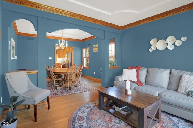 545 Walnut Woods Dr, Greenwood, IN 46142 - living room featuring a chandelier, ornamental molding, light wood-style floors, and arched walkways