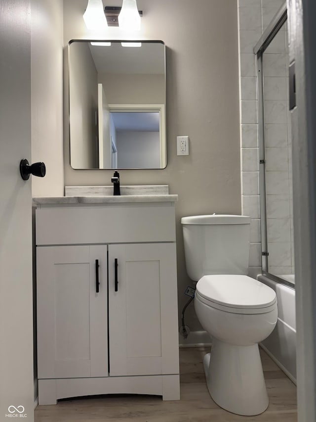 10328 Central Ave, Carmel, IN 46280 - bathroom featuring vanity, toilet, wood finished floors, enclosed tub / shower combo, and baseboards