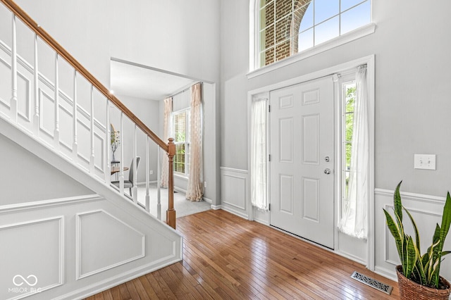 14353 Chariots Whisper Dr, Carmel, IN 46074 - foyer entrance featuring a towering ceiling, stairs, hardwood / wood-style flooring, a wainscoted wall, and a decorative wall