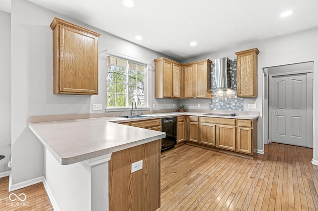 14353 Chariots Whisper Dr, Carmel, IN 46074 - kitchen with wall chimney range hood, a sink, light wood-style flooring, black appliances, and a peninsula
