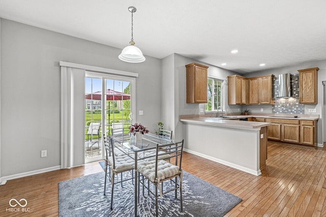 14353 Chariots Whisper Dr, Carmel, IN 46074 - kitchen featuring wall chimney range hood, light wood-style flooring, light countertops, plenty of natural light, and recessed lighting