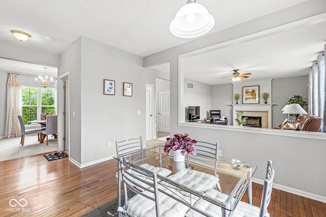 14353 Chariots Whisper Dr, Carmel, IN 46074 - dining area with a chandelier, wood-type flooring, a fireplace, baseboards, and a ceiling fan