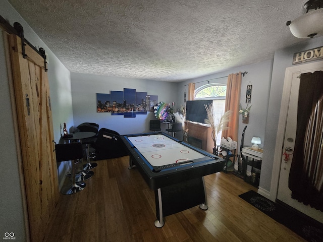 2248 Salem Park Dr, Indianapolis, IN 46239 - recreation room featuring wood finished floors, a textured ceiling, a barn door, and baseboards