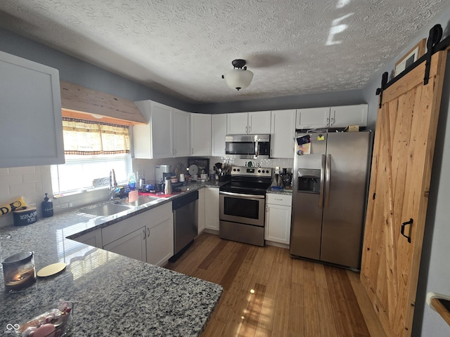 2248 Salem Park Dr, Indianapolis, IN 46239 - kitchen featuring appliances with stainless steel finishes, wood finished floors, white cabinetry, backsplash, and a textured ceiling