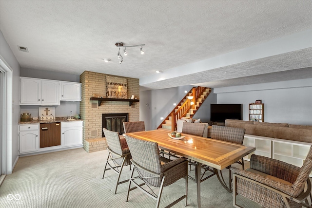 101 Edgewater Dr, Noblesville, IN 46062 - dining room featuring stairway, a brick fireplace, light carpet, and a textured ceiling