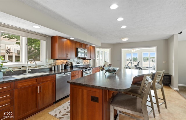 101 Edgewater Dr, Noblesville, IN 46062 - kitchen with appliances with stainless steel finishes, a sink, healthy amount of natural light, a breakfast bar, and a textured ceiling