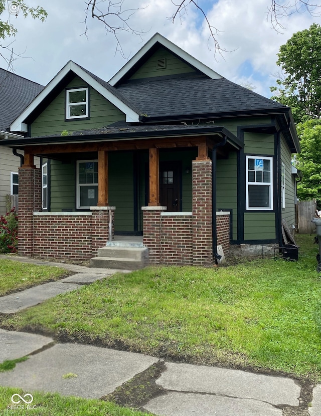 830 Villa Ave, Indianapolis, IN 46203 - view of front of home featuring a shingled roof, brick siding, a front yard, and covered porch