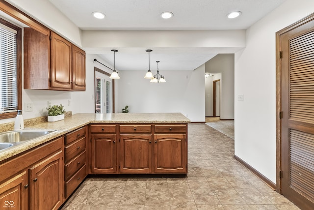 7426 N Carroll Rd, Indianapolis, IN 46236 - kitchen featuring a peninsula, light countertops, hanging light fixtures, brown cabinetry, and healthy amount of natural light