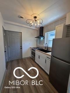2421 N Arsenal Ave, Indianapolis, IN 46218 - kitchen featuring freestanding refrigerator, wall chimney range hood, a sink, dark wood finished floors, and white cabinetry