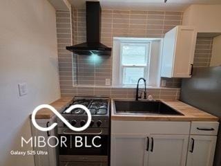 2421 N Arsenal Ave, Indianapolis, IN 46218 - kitchen featuring wall chimney exhaust hood, a sink, white cabinets, light countertops, and tasteful backsplash