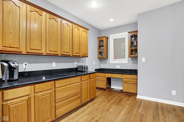 14492 Allison Dr, Carmel, IN 46033 - kitchen featuring glass insert cabinets, light wood-type flooring, built in desk, dark stone counters, and recessed lighting