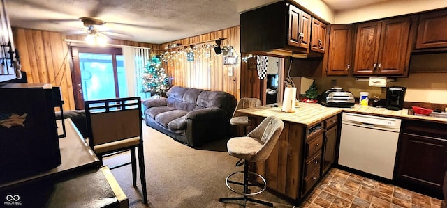 1619 Crest Ct, Indianapolis, IN 46214 - kitchen featuring white dishwasher, tile counters, ceiling fan, wooden walls, and dark brown cabinetry