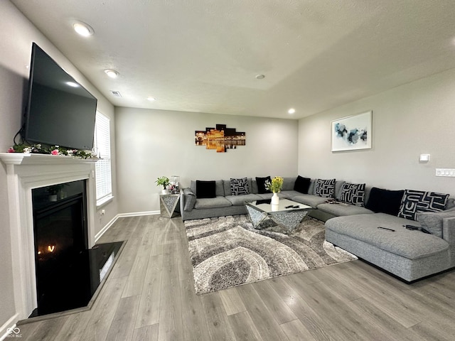 9133 Thames Dr, Avon, IN 46123 - living area featuring wood finished floors, a glass covered fireplace, baseboards, and recessed lighting
