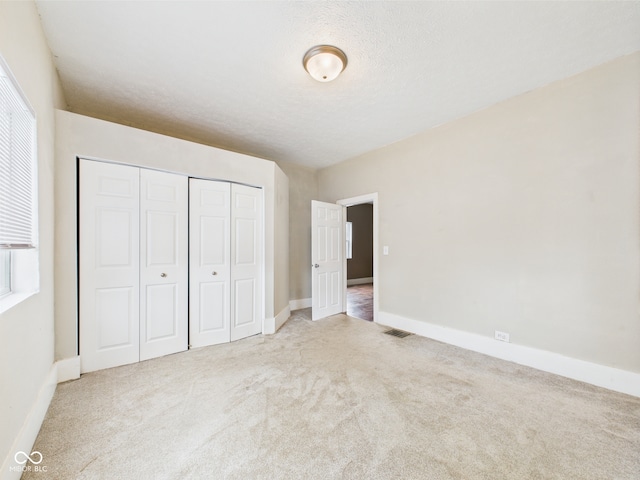 907 S A St, Elwood, IN 46036 - unfurnished bedroom with carpet flooring, a closet, baseboards, and multiple windows