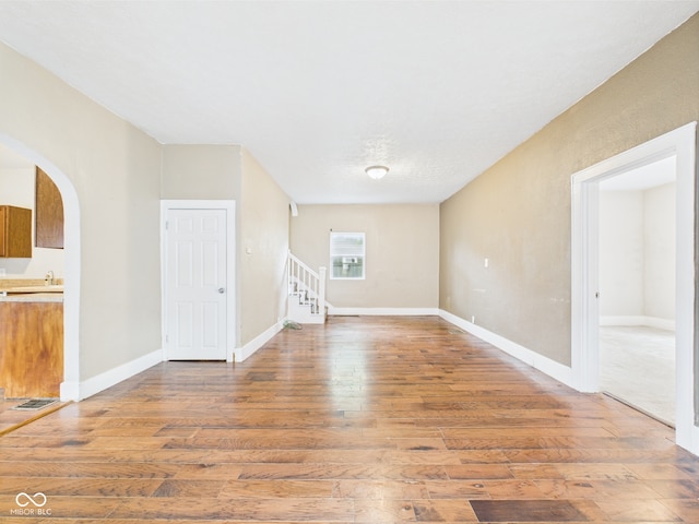 907 S A St, Elwood, IN 46036 - spare room featuring wood finished floors, arched walkways, stairs, and baseboards