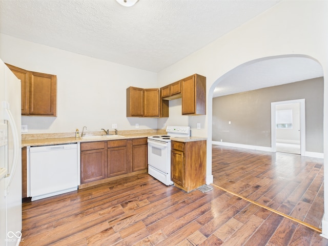 907 S A St, Elwood, IN 46036 - kitchen featuring white appliances, arched walkways, dark wood-style floors, a sink, and brown cabinets