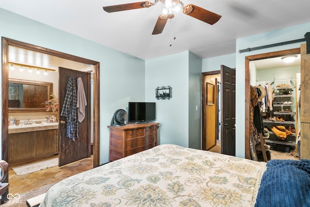 3480 W Broadus Dr, North Vernon, IN 47265 - bedroom featuring a barn door, a sink, a spacious closet, a ceiling fan, and ensuite bathroom