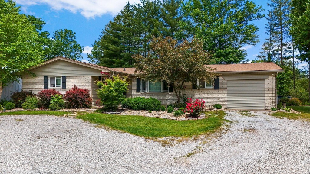 3480 W Broadus Dr, North Vernon, IN 47265 - ranch-style house featuring gravel driveway, a garage, and brick siding