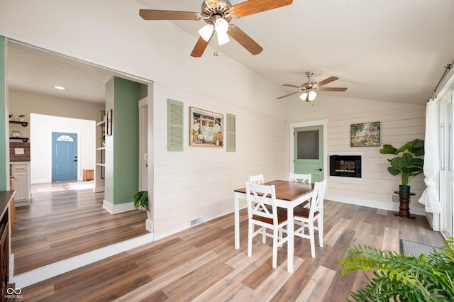 3360 Main St, Plainfield, IN 46168 - dining space featuring vaulted ceiling, wood finished floors, a ceiling fan, a glass covered fireplace, and baseboards